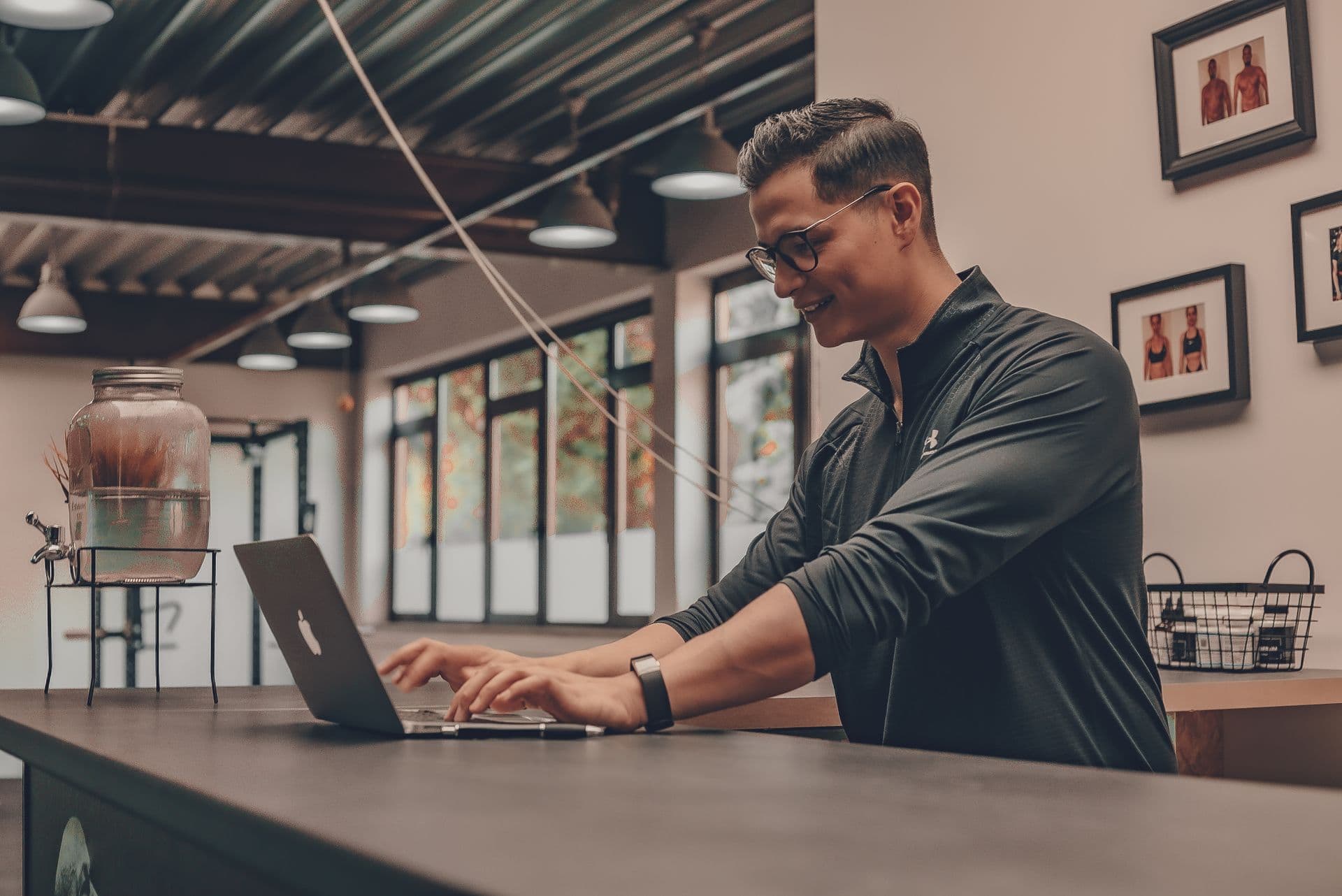 A gym staff member answers messages on a laptop at the front desk