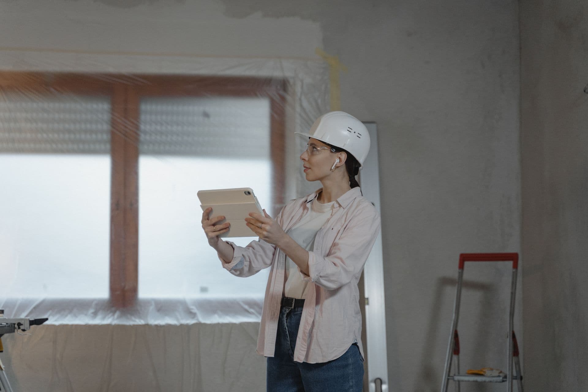 A contractor checks a job on a tablet inside a house