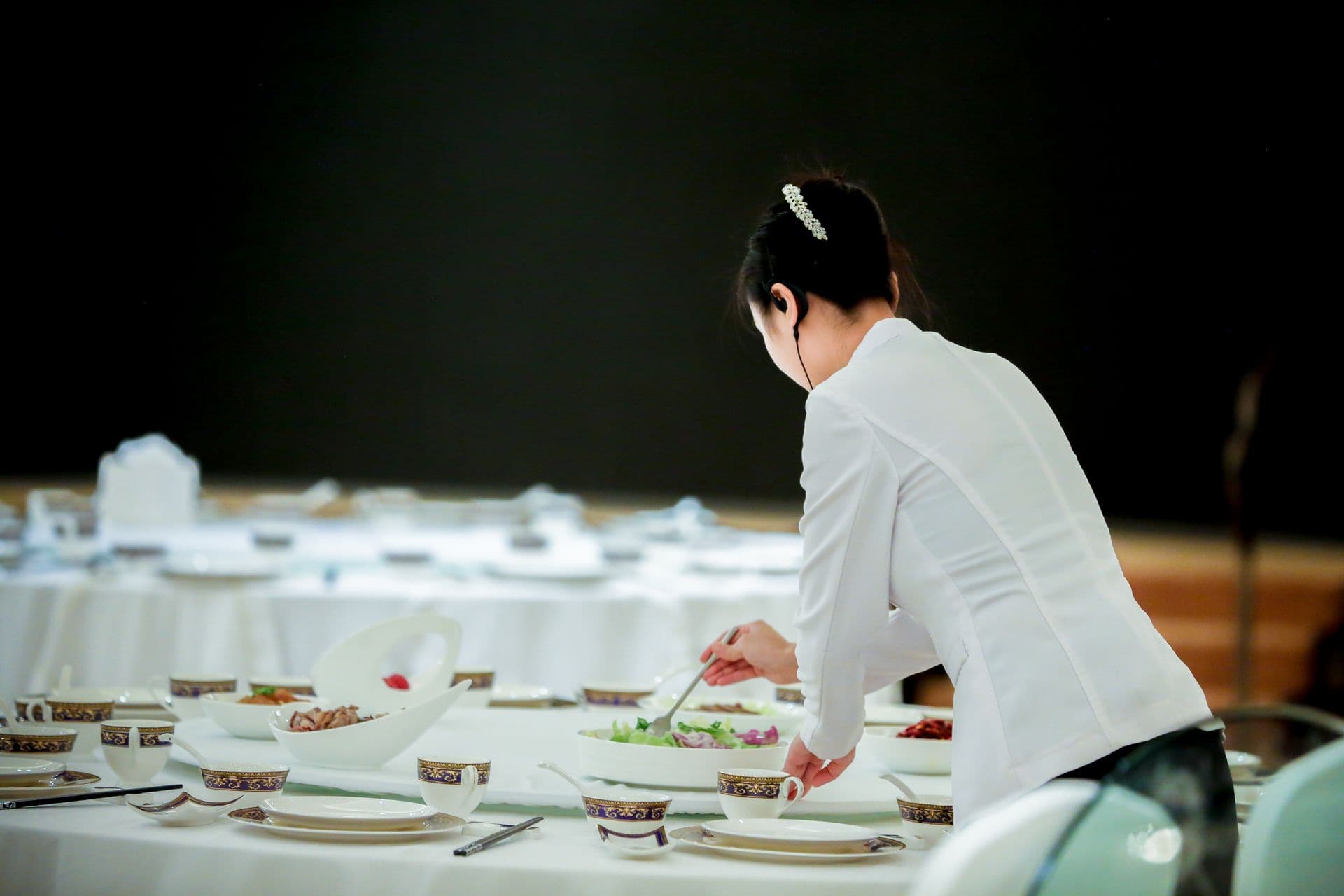 A server sets a long table for a private dinner