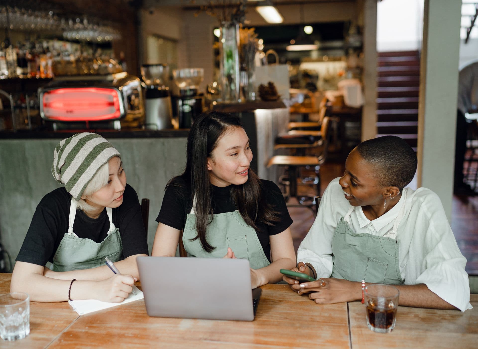 Restaurant staff in aprons plan the week on a laptop