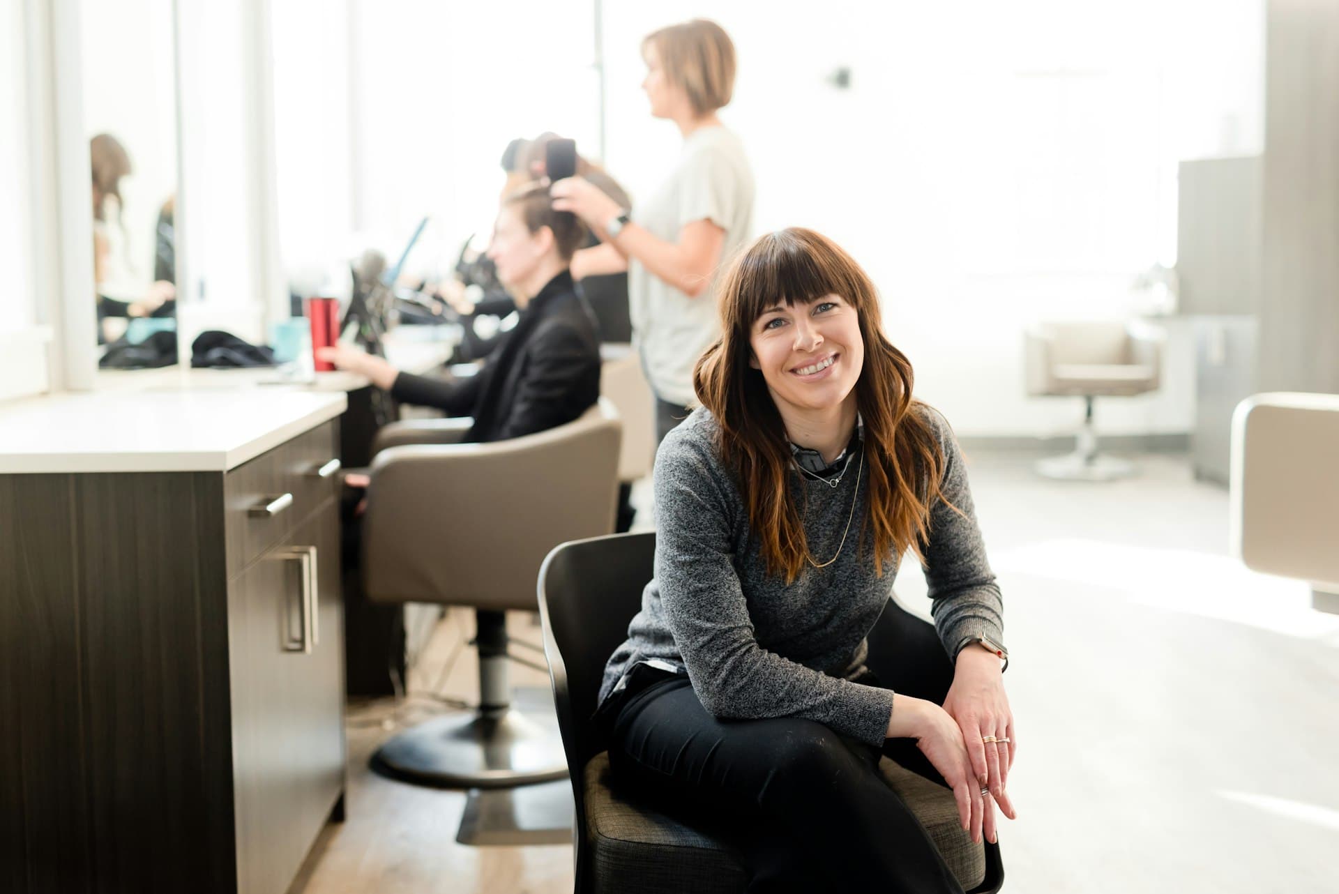 A salon owner in her salon, her team at work behind her
